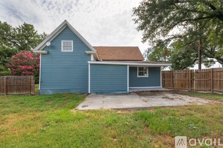 A blue house with a brown roof and a fence in front.