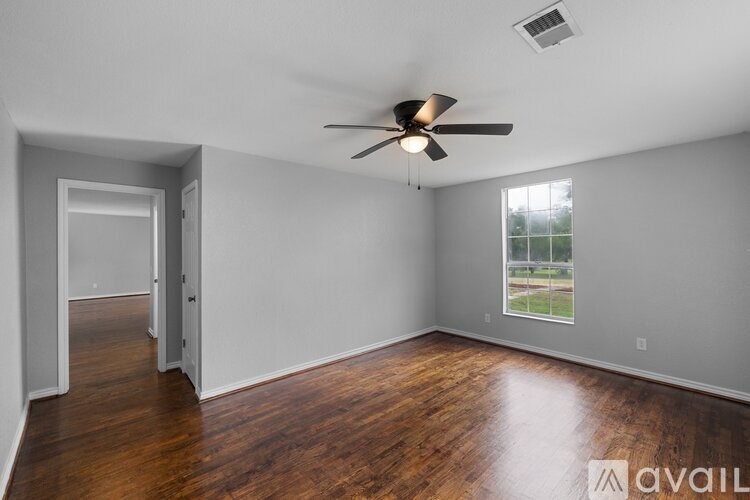 A room with a ceiling fan and wooden floors.