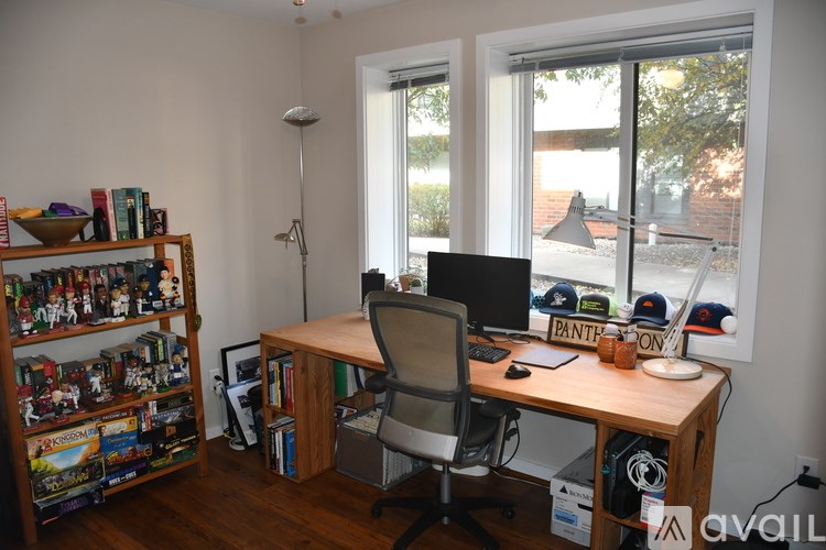 A room with a desk, chair, and a bookshelf filled with various items.
