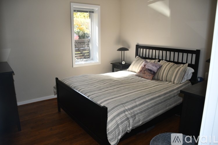 A bedroom with a bed, nightstand, and window.