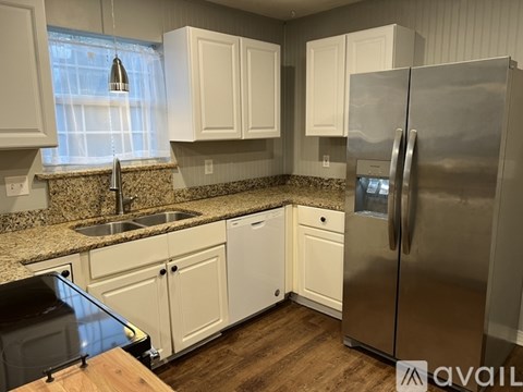 A kitchen with white cabinets and a stainless steel refrigerator.