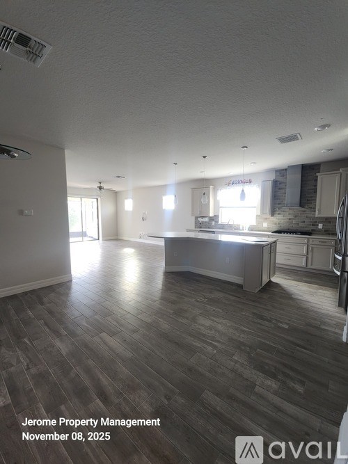 A spacious kitchen and living room with wood flooring and white walls.