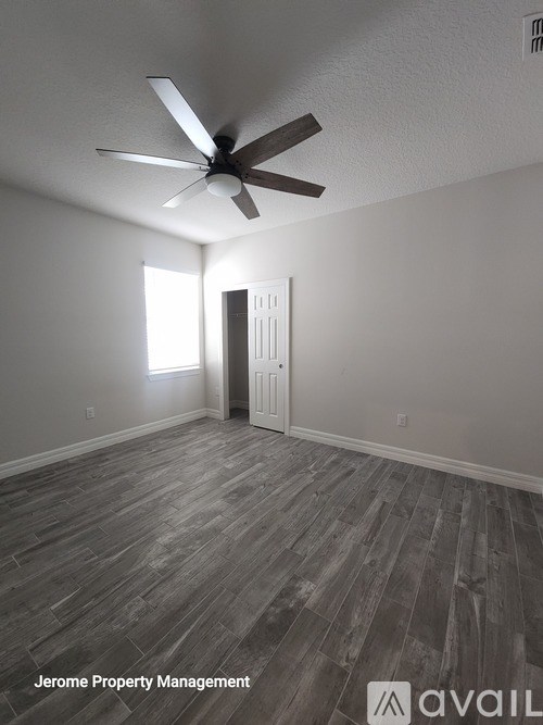 A room with a ceiling fan and wooden flooring.