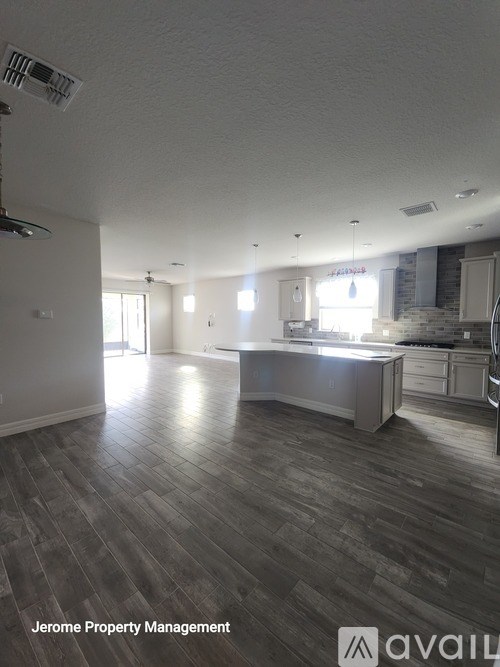 A spacious kitchen and living room with wood flooring and white walls.