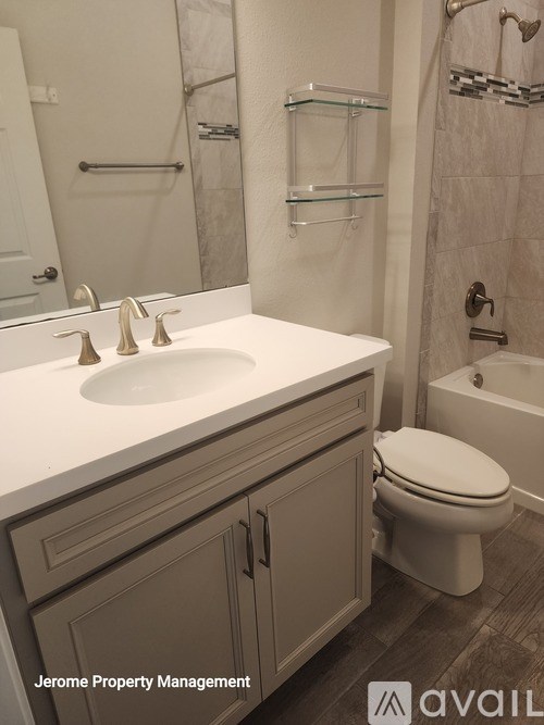 A white toilet sits in a bathroom with a glass shelf above it.