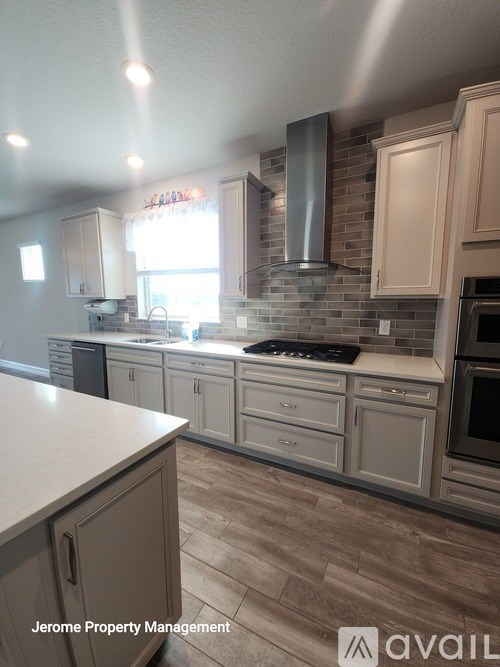 A kitchen with a tile backsplash and a stove top oven.