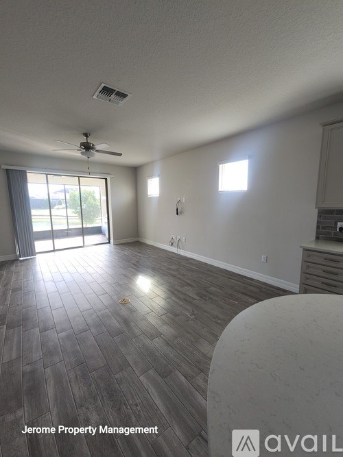 A spacious room with a ceiling fan and sliding glass doors leading to a balcony.