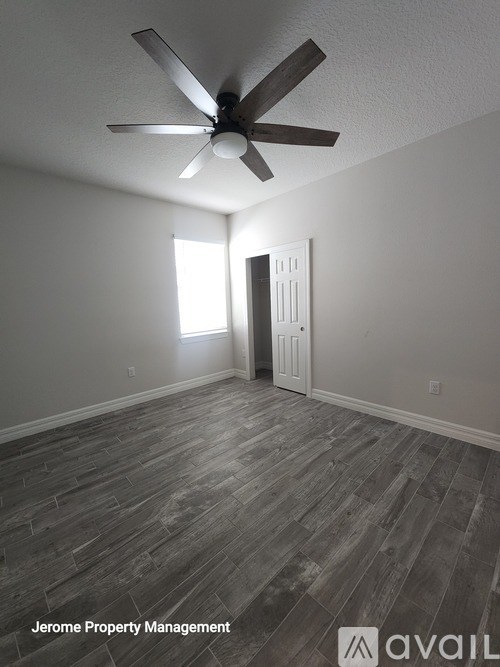 A room with a ceiling fan and wooden flooring.
