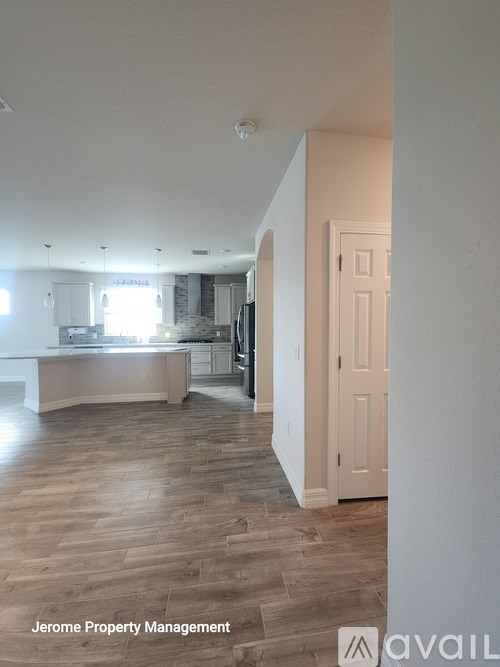 A spacious kitchen with wooden flooring and white walls.