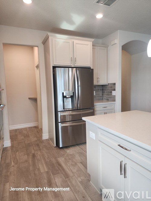 A kitchen with a refrigerator, cabinets, and a countertop.