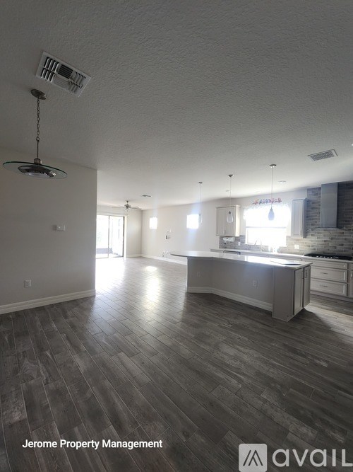 A large, empty room with wood flooring and a ceiling fan.