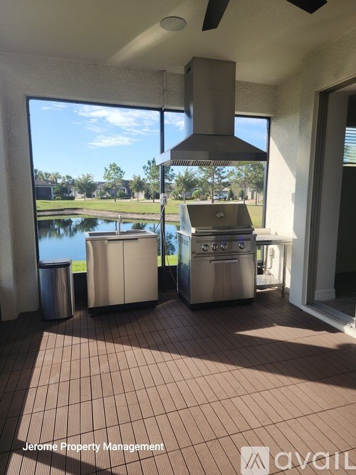 A patio with a grill and a window overlooking a body of water.