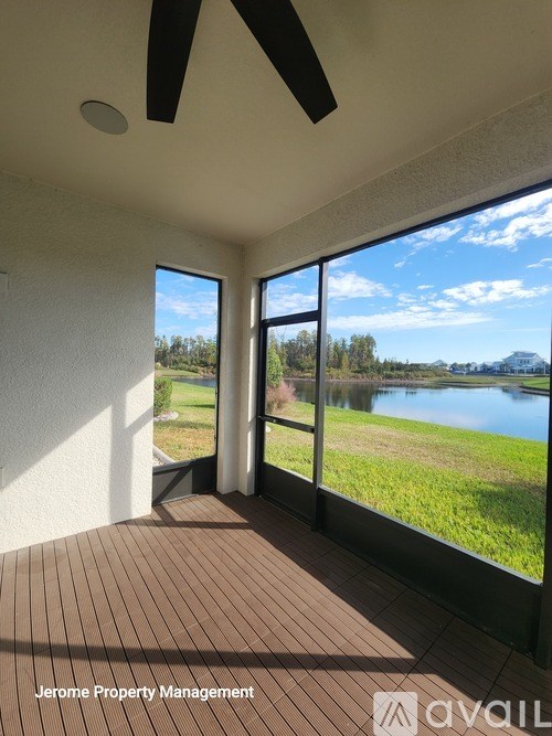 A room with a ceiling fan and a view of a lake.