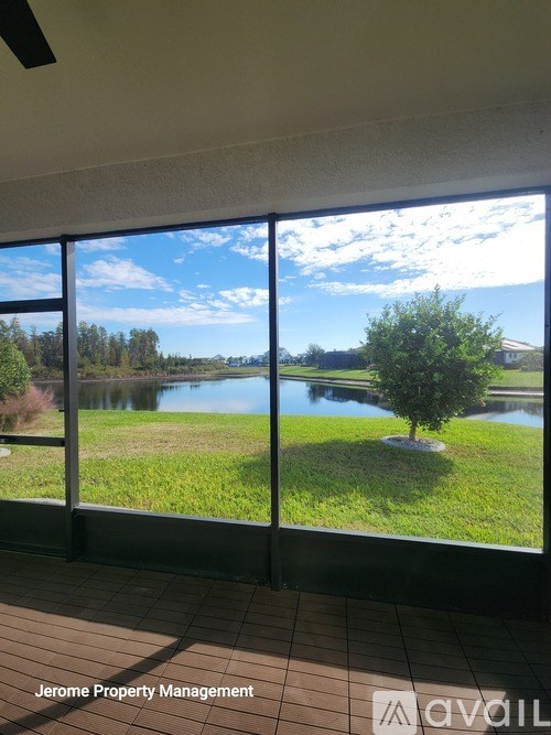 A room with a view of a lake and trees through a large window.