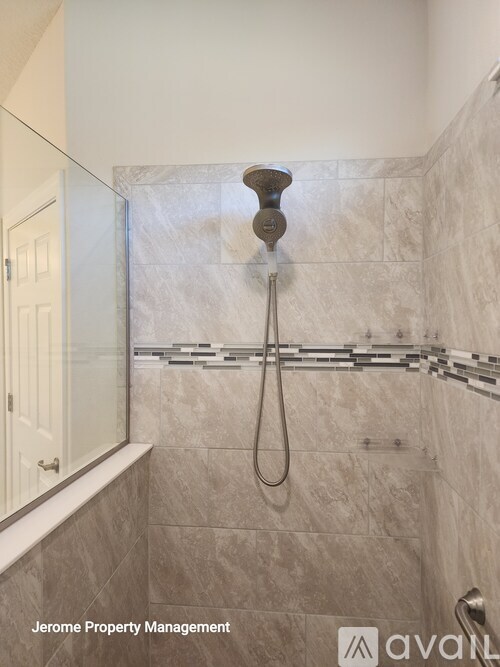 A bathroom with a marble tile shower and a white door.