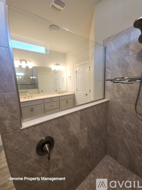 A bathroom with a large mirror and a shower area.
