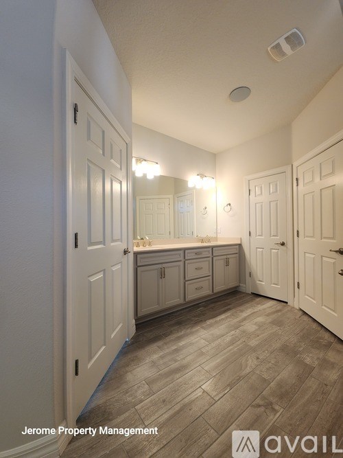 A well-lit, empty room with wooden flooring and white walls.