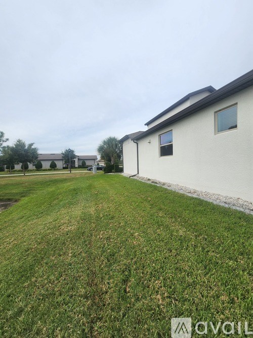 A grassy area in front of a white house with a sign that says "available".
