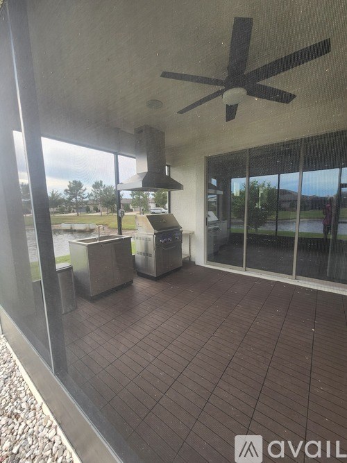 A patio with a ceiling fan and a glass door leading to a backyard.