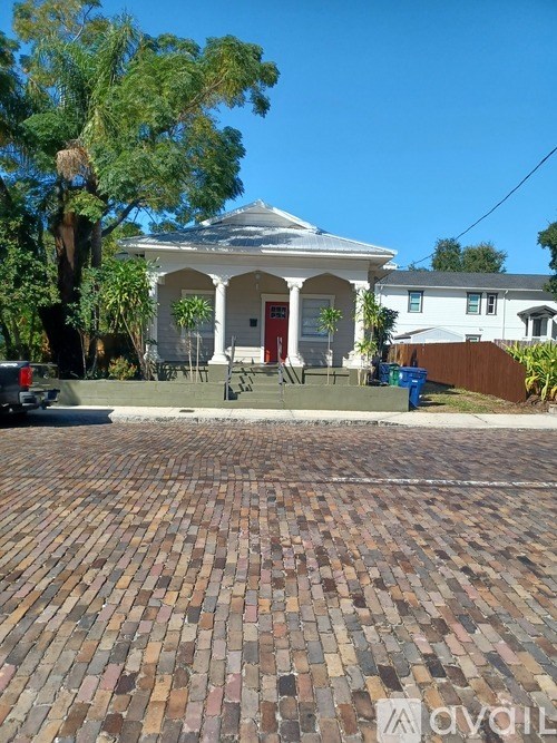 A white house with a red door and a brick driveway.
