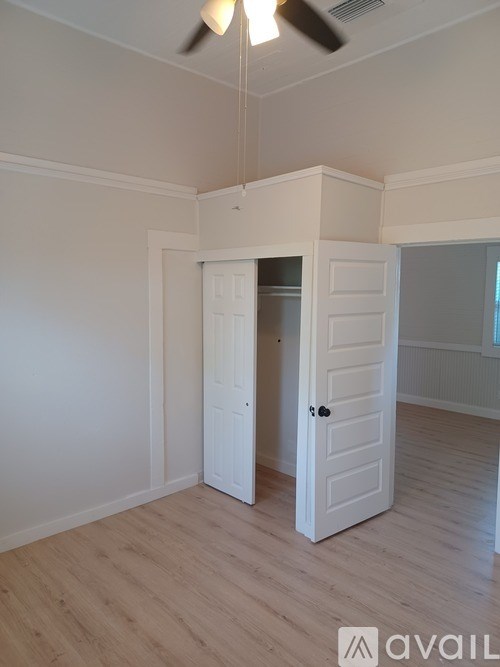 A room with a white door and a ceiling fan.
