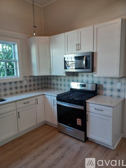 A kitchen with white cabinets and a black stove top oven.