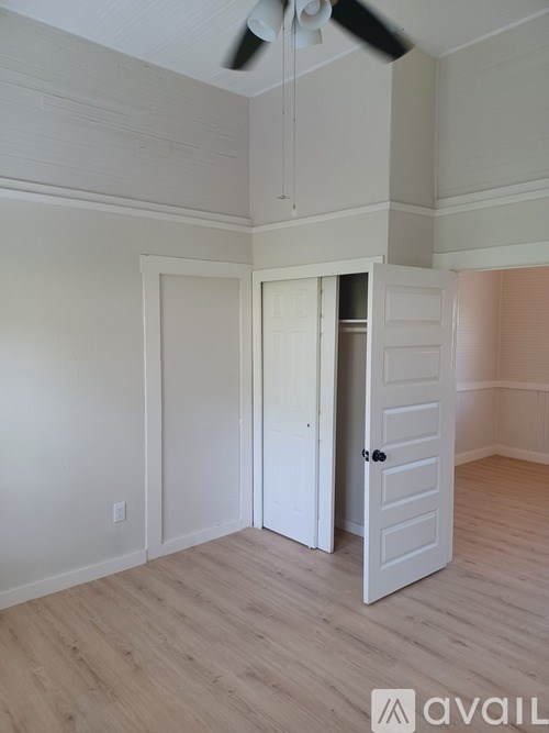A room with a white door and a fan on the ceiling.