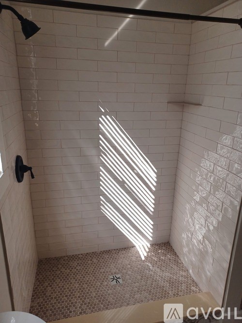 A bathroom with a white tiled shower and a toilet.