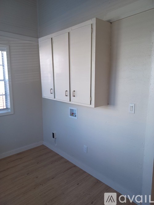 A room with a window and a white cabinet with three doors.
