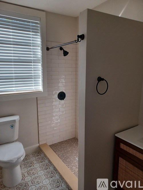 A bathroom with a toilet, a shower, and a towel rack.
