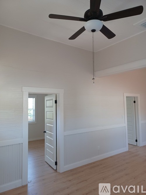 A room with a ceiling fan and two doors.
