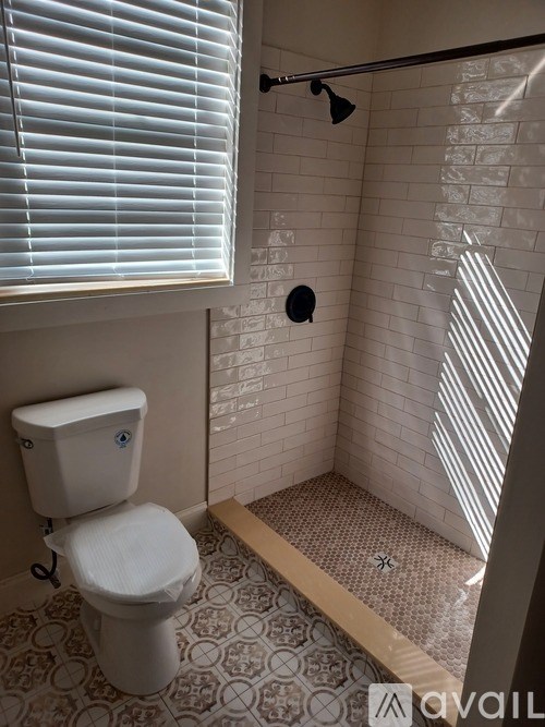 A white toilet in a small bathroom with a tiled floor and shower.
