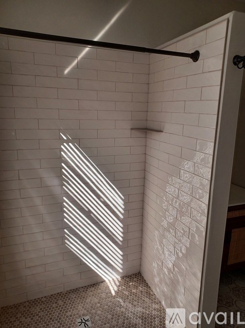 A white tiled bathroom with a light on the wall.