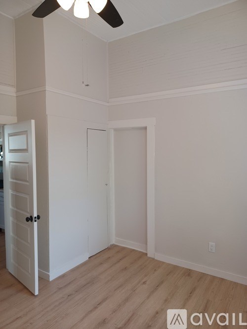 A room with a white door and a white ceiling fan.