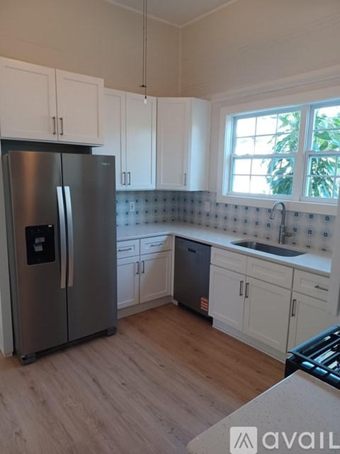 A kitchen with a stainless steel refrigerator and white cabinets.
