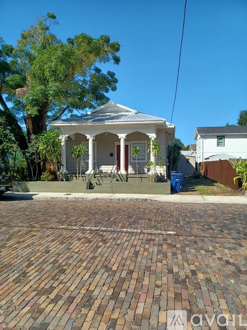 A white house with a red door and a brick driveway.