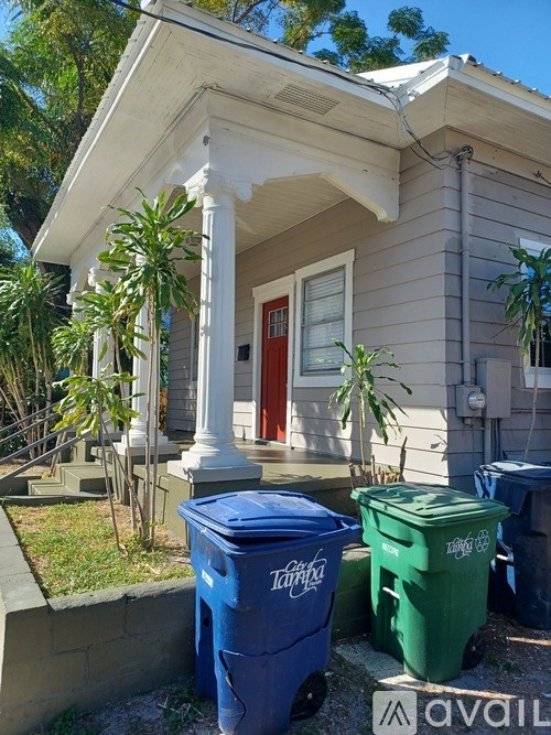 A house with a red door and two trash bins in front.
