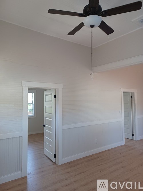 A room with a ceiling fan and a doorway leading to another room.