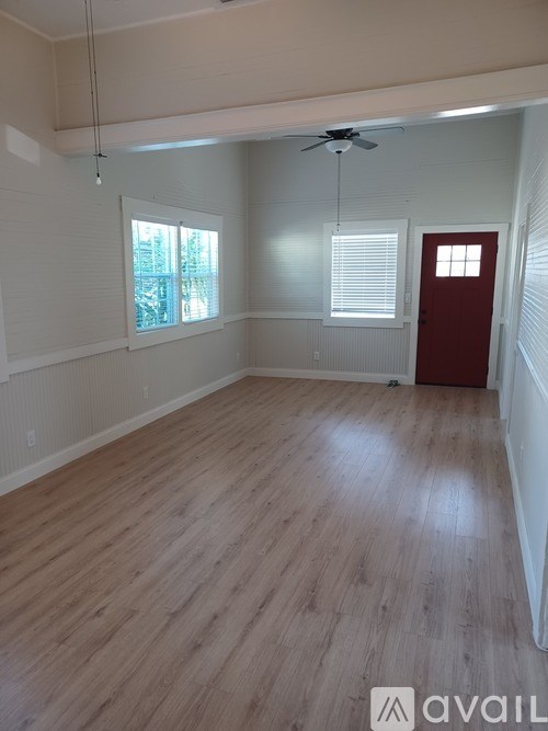 A room with wooden flooring and a red door.