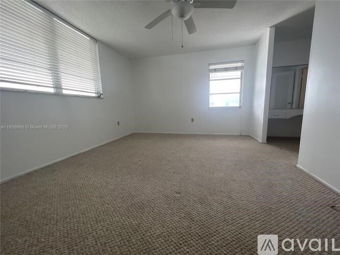 A room with a carpeted floor, a ceiling fan, and a window with blinds.
