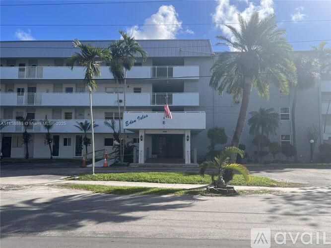 A white building with palm trees in front of it.