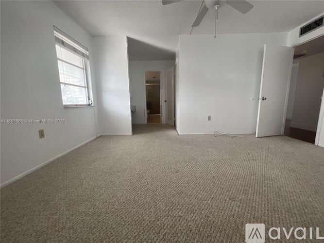 A room with a carpeted floor, a ceiling fan, and a window with blinds.