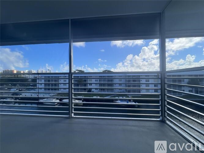 A view of a parking lot through a window with a metal railing.
