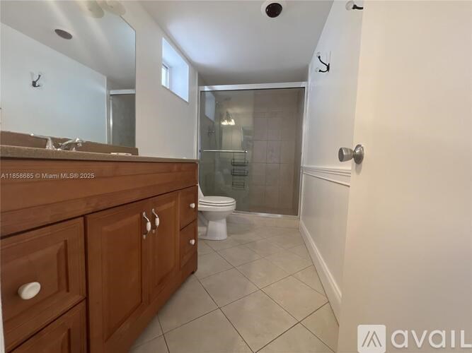 A bathroom with a wooden vanity and a walk-in shower.