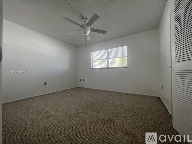 A room with a ceiling fan and carpeted floor.