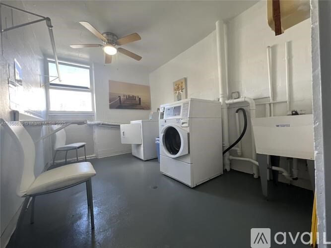 A laundry room with a washer and dryer, a fan, and a chair.