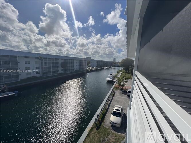 A sunny day with clouds and a body of water in front of a building.