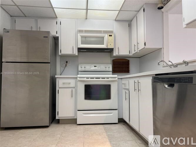 A kitchen with white cabinets and appliances including a refrigerator, oven, and microwave.