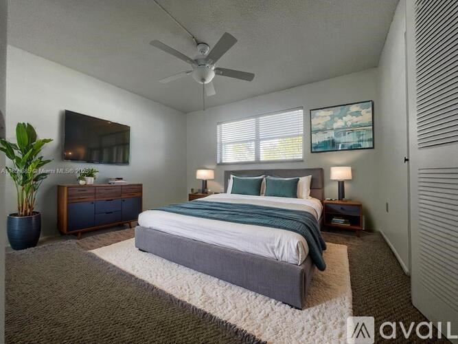 A bedroom with a large bed, a ceiling fan, and a potted plant.
