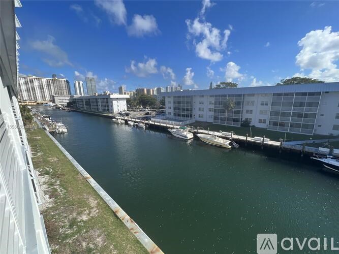 A view of a marina with boats docked in the water and buildings in the background.